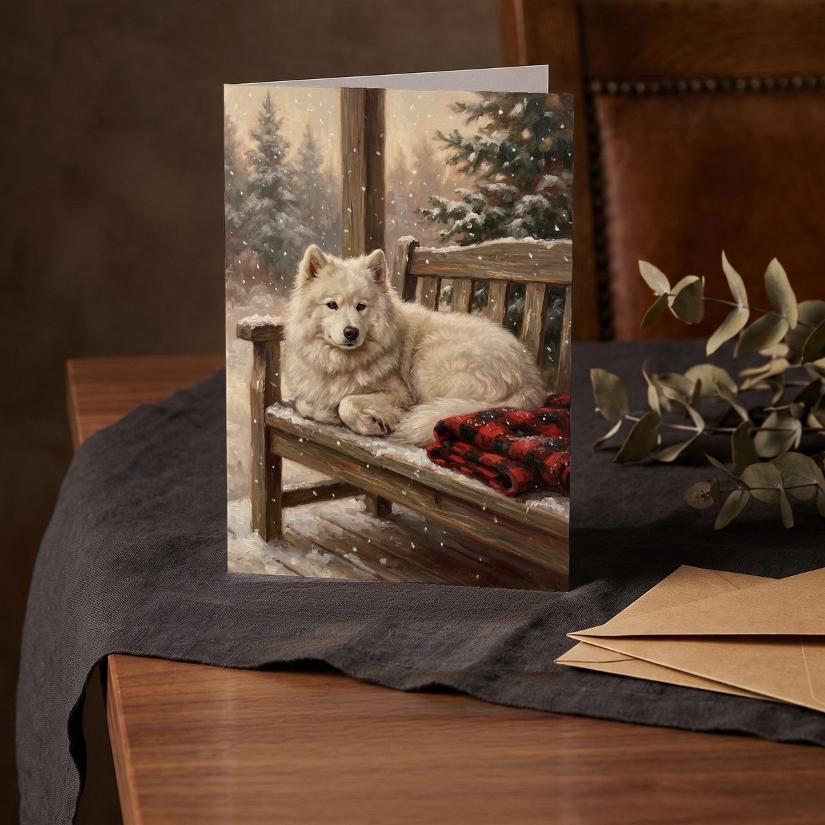 A folded card standing on a charcoal linen cloth with a sprig of dried eucalyptus