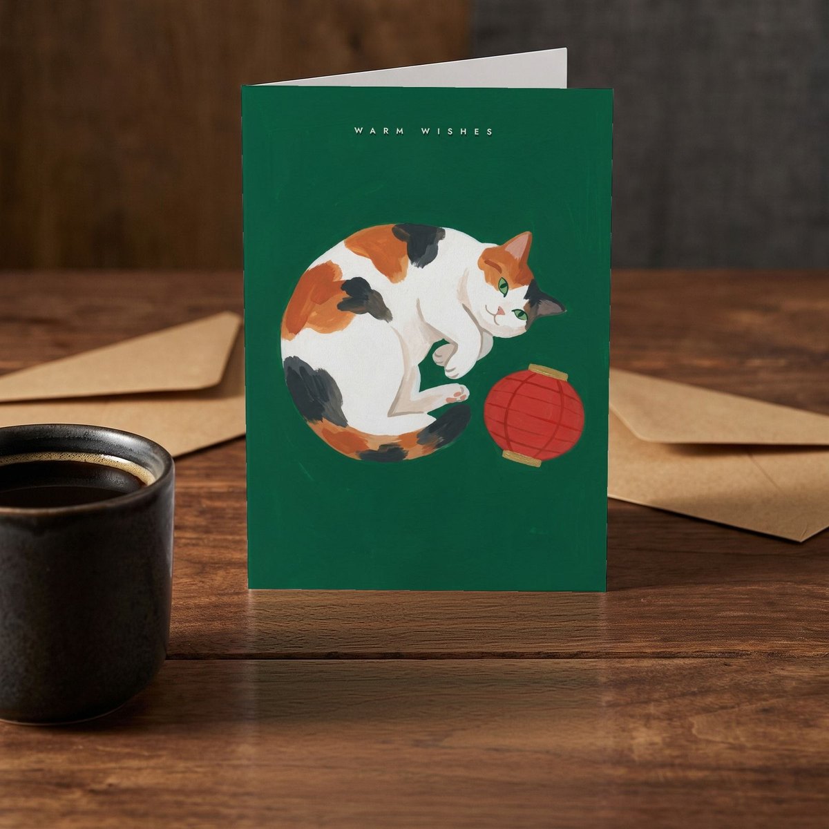 A folded card standing on a rustic wood table beside a mug of coffee