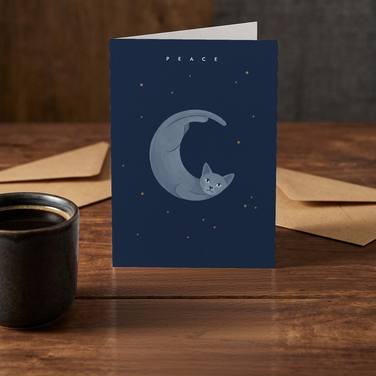 A folded card standing on a rustic wood table beside a mug of coffee